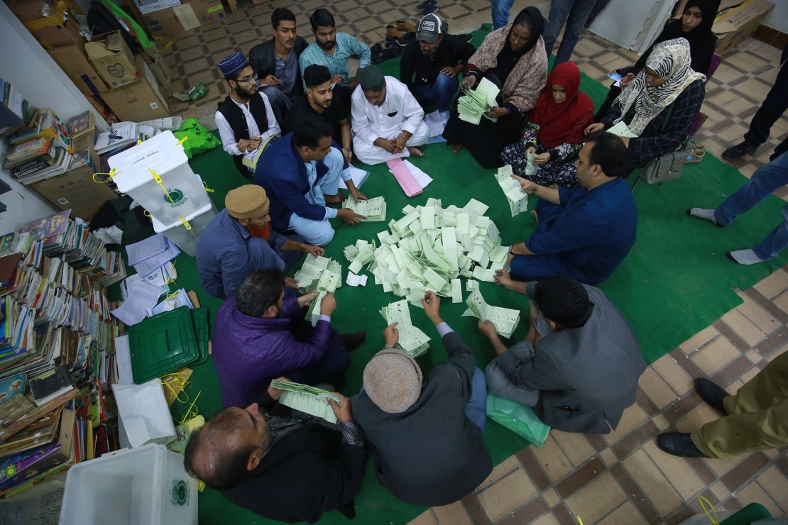Election officials empty ballot boxes to count votes cast in Karachi.