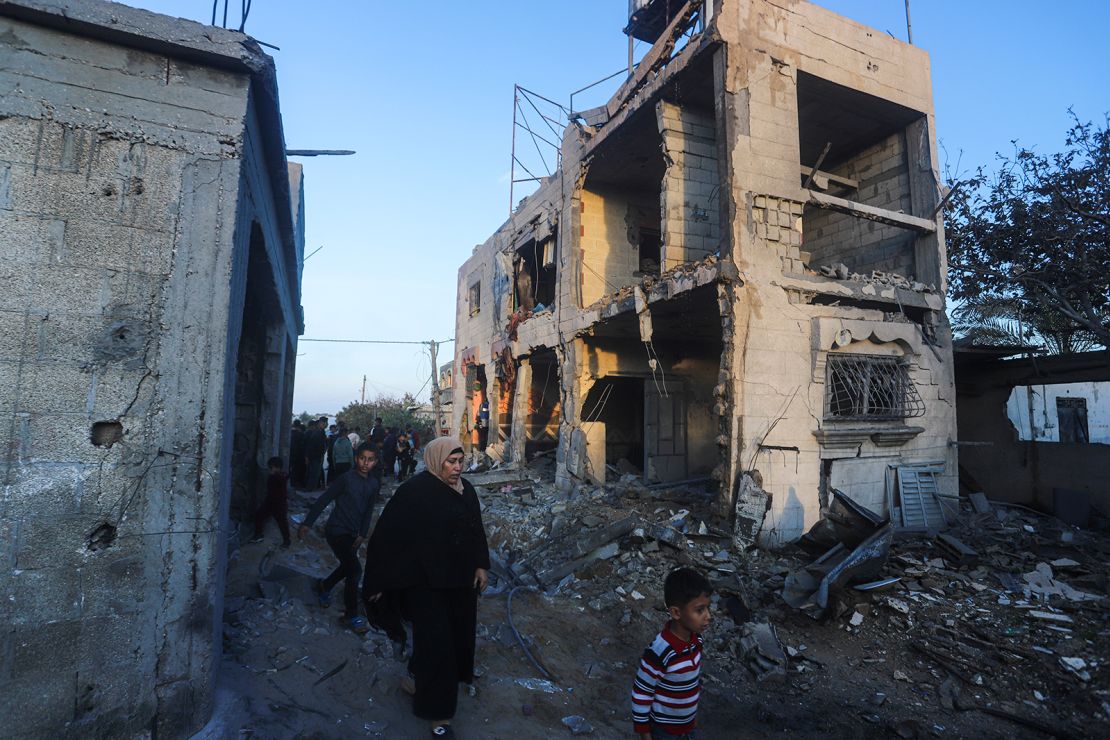 Palestinians walk by a residential building destroyed in an Israeli strike in Rafah, Gaza Strip, February 11, 2024.