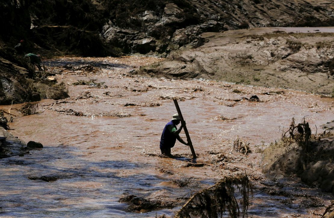 A man uses a stick to cross a river after heavy flash floods wiped out several homes when a dam burst, following heavy rains in Kamuchiri village of Mai Mahiu, Nakuru County, Kenya on April 29, 2024.