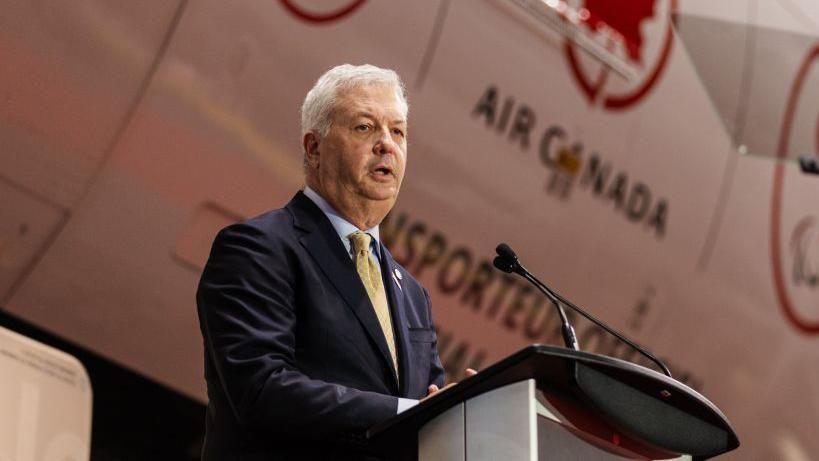 Air Canada CEO Michael Rousseau speaks at a corporate event, as the airline announces his planned retirement following recent controversy.