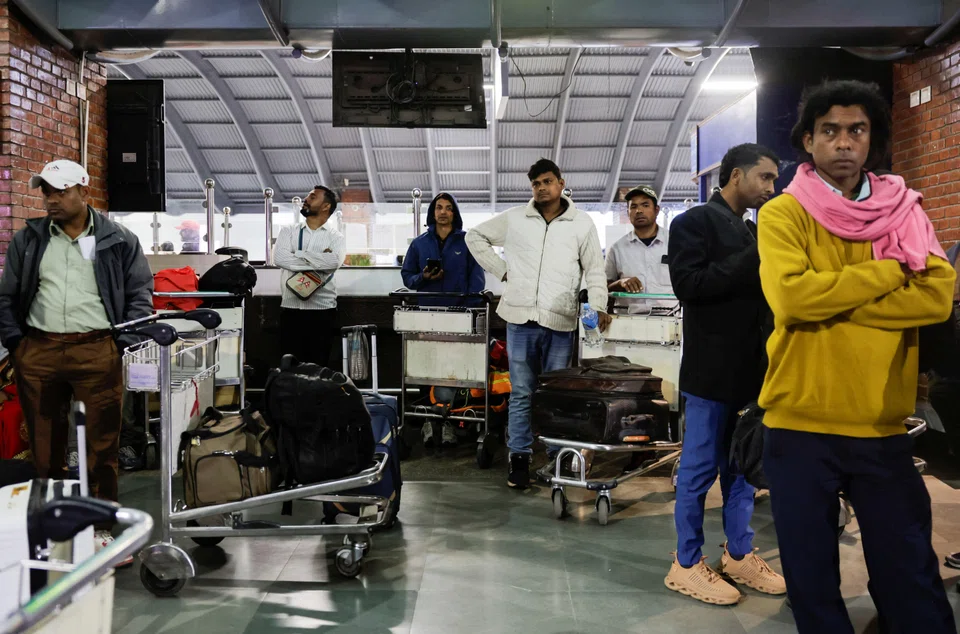 Travelers check digital flight information boards showing widespread cancellations at an international airport as global airlines suspend schedules due to airspace closures linked to the U.S.–Iran conflict.